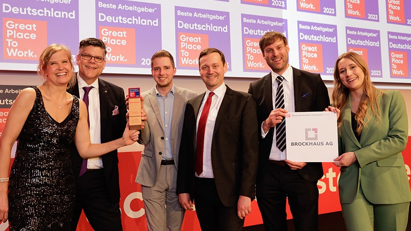 Ein Gruppenfoto der Mitarbeitenden der Brockhaus AG, die ihre Trophäe bei der Siegerehrung von Great Place to Work 2023 halten. Sie strahlen vor Freude und zeigen stolz ihre Auszeichnung als einer der besten Arbeitgeber Deutschlands.